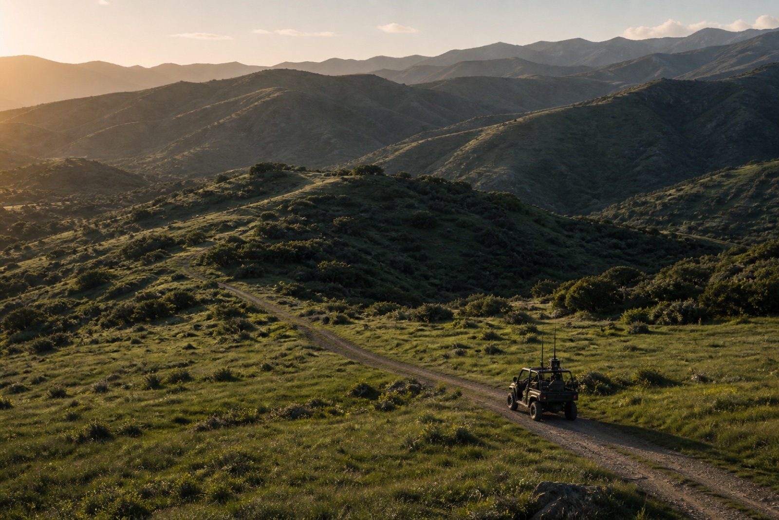 Small unbranded field vehicle moving through green foothills.